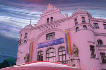 Ein bearbeitetes Foto der Volksoper Wien von außen vor einem gemalten, dunkelblauen Himmel.