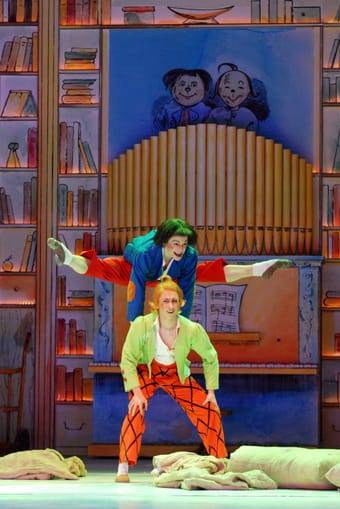 Zwei Balletttänzer verkörpern Max und Moritz auf der Bühne vor einer fantasievollen Kulisse. Kostüme und Bühne erinnern an das Bilderbuch von Wilhelm Busch.